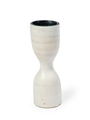 a white vase with a black top sitting on a white surface