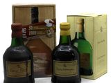 trois bouteilles d'alcool posées à côté d'un carton de vin