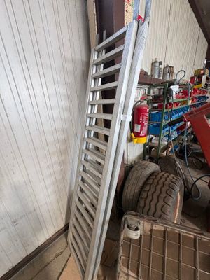 une échelle appuyée contre un mur, à côté d'un tas de pneus