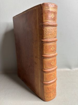 un vieux livre marron posé sur une table blanche