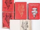 six red books sitting on top of each other on a white surface