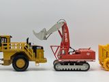 three toy construction vehicles that are on a white surface
