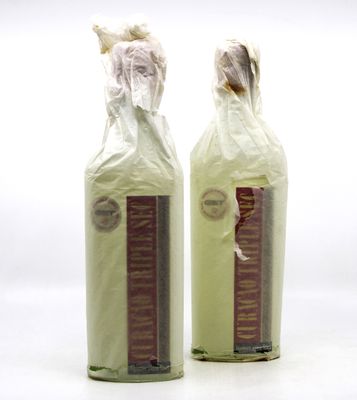 deux bouteilles de vin emballées dans du plastique, posées sur une table