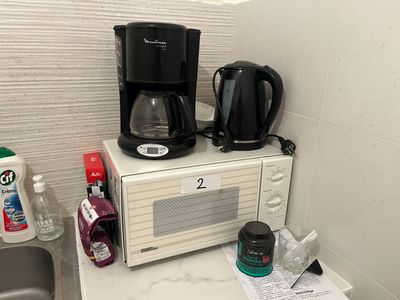 un micro-ondes et une cafetière posés sur le plan de travail d'une cuisine