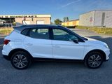 une voiture blanche garée dans un parking à côté d'un bâtiment