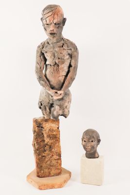 sculpture of a man sitting on a rock next to a busturine of a man