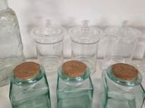 five glass jars with cork lids on a white surface