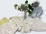 a bunch of baby clothes and a vase of flowers on the table