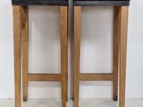 two wooden stools sitting next to each other against a white wall