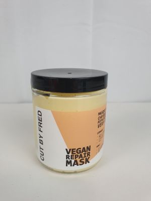un gros plan sur un pot de masque réparateur vegan posé sur une surface blanche