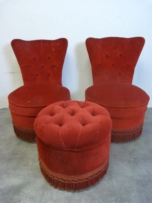 une paire de fauteuils et de poufs en velours rouge, ornés de franges