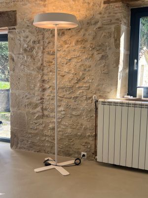 Lampadaire en métal laqué blanc sur piètement cruciforme.