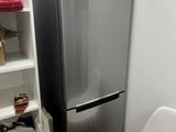 a silver refrigerator and a white chair in a room