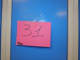 un post-it rose sur une porte bleue, sur laquelle est collé un autocollant