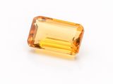 a yellow sapphire stone on a white surface