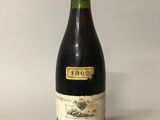 an old bottle of wine sitting on top of a white table