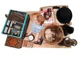a doll sitting on the floor next to a pile of items