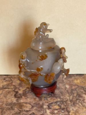a small glass vase with a figurine on top of it