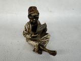 a small statue of a man sitting on a white surface