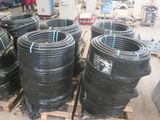 de nombreux tuyaux noirs empilés sur des palettes dans un entrepôt