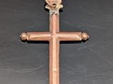 une croix en bois posée sur une surface noire, dans laquelle est insérée une clé
