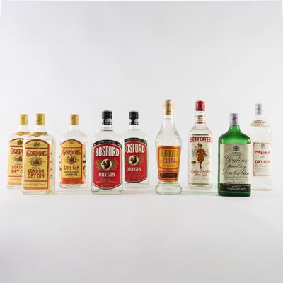 plusieurs types de bouteilles d'alcool alignées sur une surface blanche