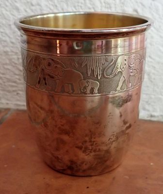 une tasse en métal posée sur une table en bois
