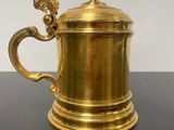 an antique brass coffee pot with a dragon handle on a black table
