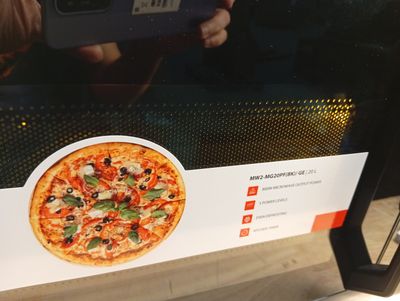 someone taking a picture of a pizza with a cell phone