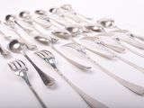de nombreuses fourchettes et cuillères disposées sur la table