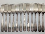 six forks and a knife are lined up on a white surface