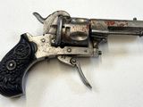 un vieux revolver argenté avec une crosse noire sur un fond blanc