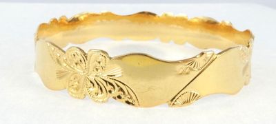 an image of a close up of a gold bracelet on a white surface