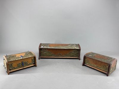 trois morceaux de bois ornés de décorations métalliques, posés sur une surface blanche