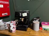 une cafetière et des tasses posées sur un plan de travail dans une pièce