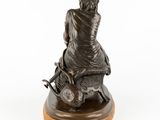 an image of a bronze statue of a man sitting on top of a table