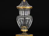 un vase ancien en verre posé sur un socle, orné de motifs dorés