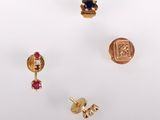trois paires de boucles d'oreilles en or et une bague posées sur un fond blanc