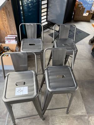 four metal stools sitting on top of a tiled floor next to a window