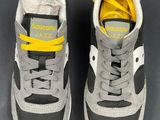 grey and yellow sneakers with yellow laces on them on a gray surface