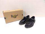 pair of black leather shoes sitting next to a cardboard box