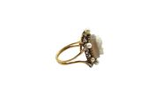 a close up of a gold ring with pearls and a stone