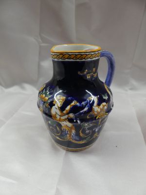 un vase bleu et or posé sur une surface blanche