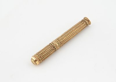 une pipe ancienne en laiton avec un manche en bois posée sur une surface blanche
