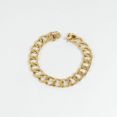 gros plan d'un bracelet en chaîne en or sur fond blanc