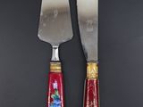 pair of red and gold handled knives on a black surface