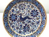 a blue and gold plate with a deer on it