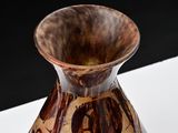a brown and black vase sitting on a white table