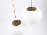 a pair of white glass and brass pendant lights hanging from the ceiling