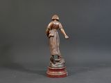 bronze statue of a woman holding a basket of flowers on a pedestal